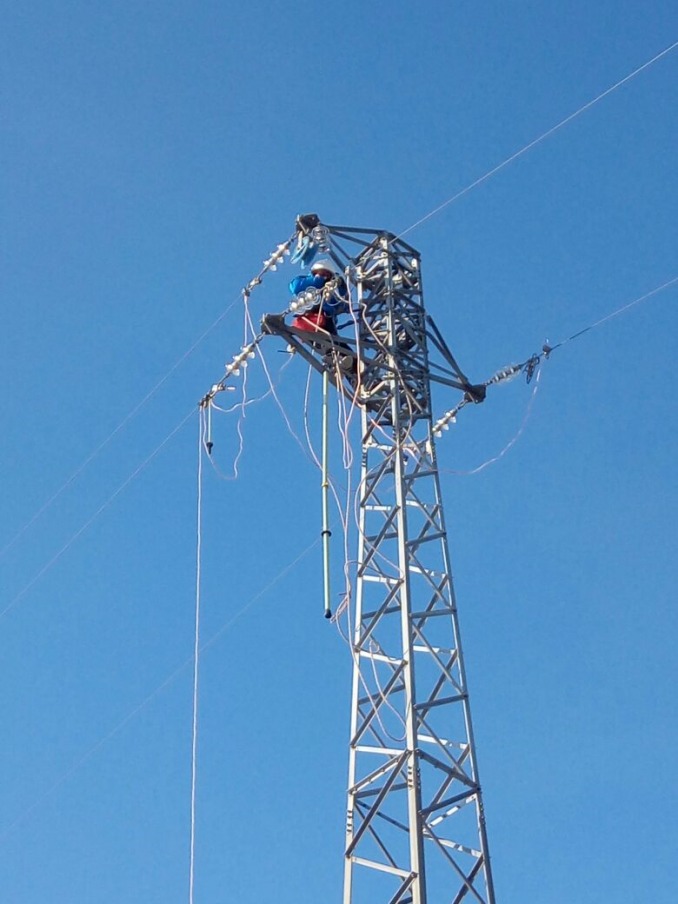 Intervento ravvicinato sulla sommità di un traliccio per il ripristino di una linea elettrica aerea